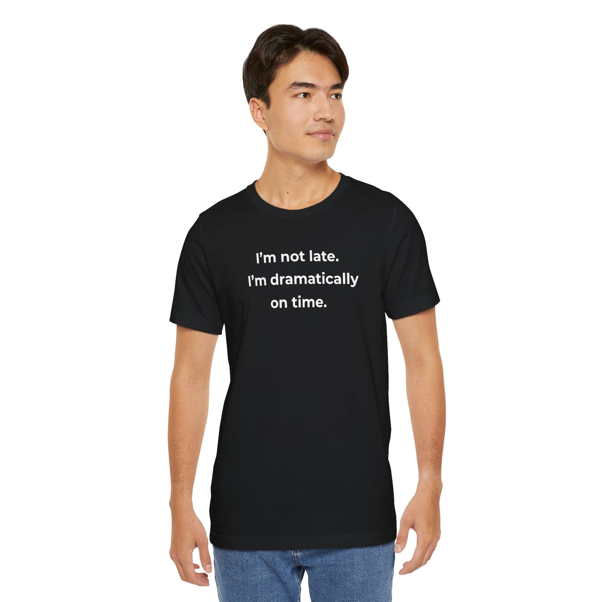 Man wearing a black t-shirt with humorous text 'I'm not late. I'm dramatically on time' design on a white background