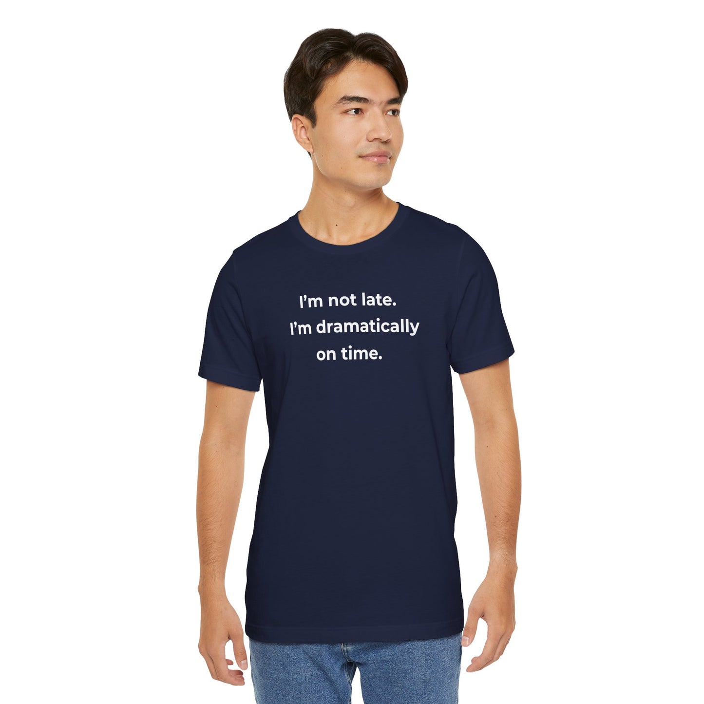 Man wearing a navy blue t-shirt with humorous text 'I'm not late. I'm dramatically on time' on a white background