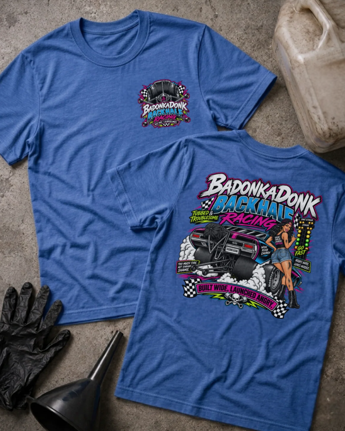 Front and back of Badonkadonk Backhalf Racing heather true royal T-shirt with chest logo, woman beside a drag car with wide rear tires and wheelie bars, and “Built wide, launched angry” slogan.