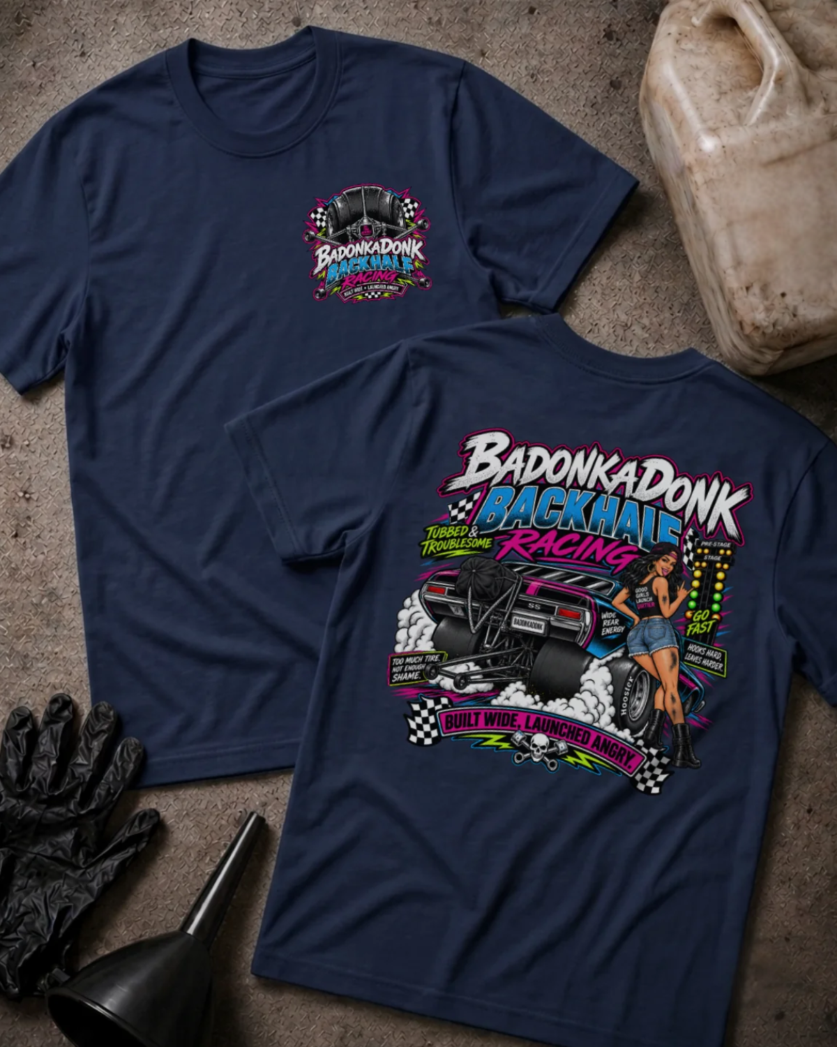 Front and back of Badonkadonk Backhalf Racing navy T-shirt with chest logo, woman beside a drag car with wide rear tires and wheelie bars, and “Built wide, launched angry” slogan.