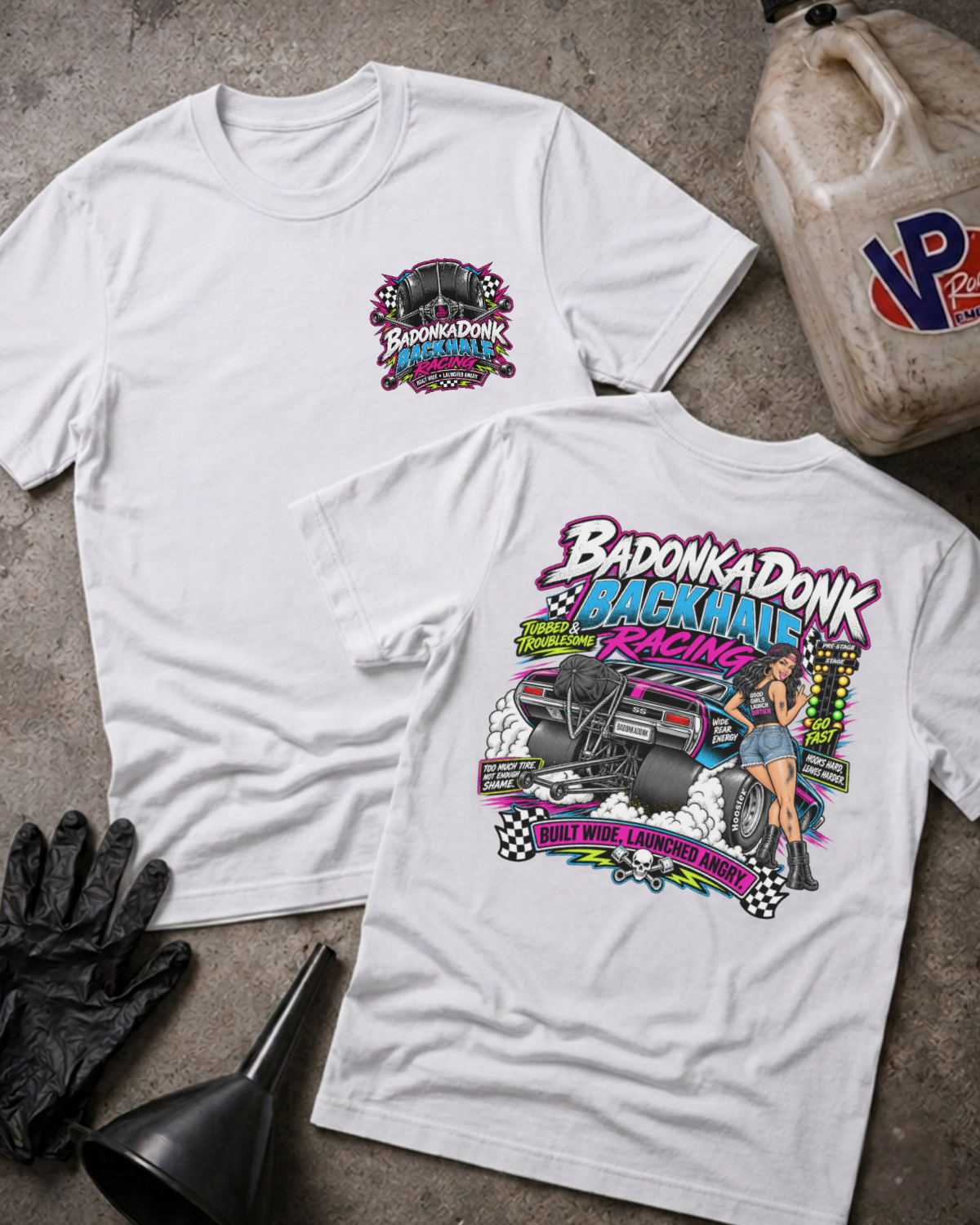 Two white graphic T-shirts laid flat on a concrete surface, showing the front and back designs. The front has a small chest graphic reading 'BADONKADONK BACKHALF RACING'.