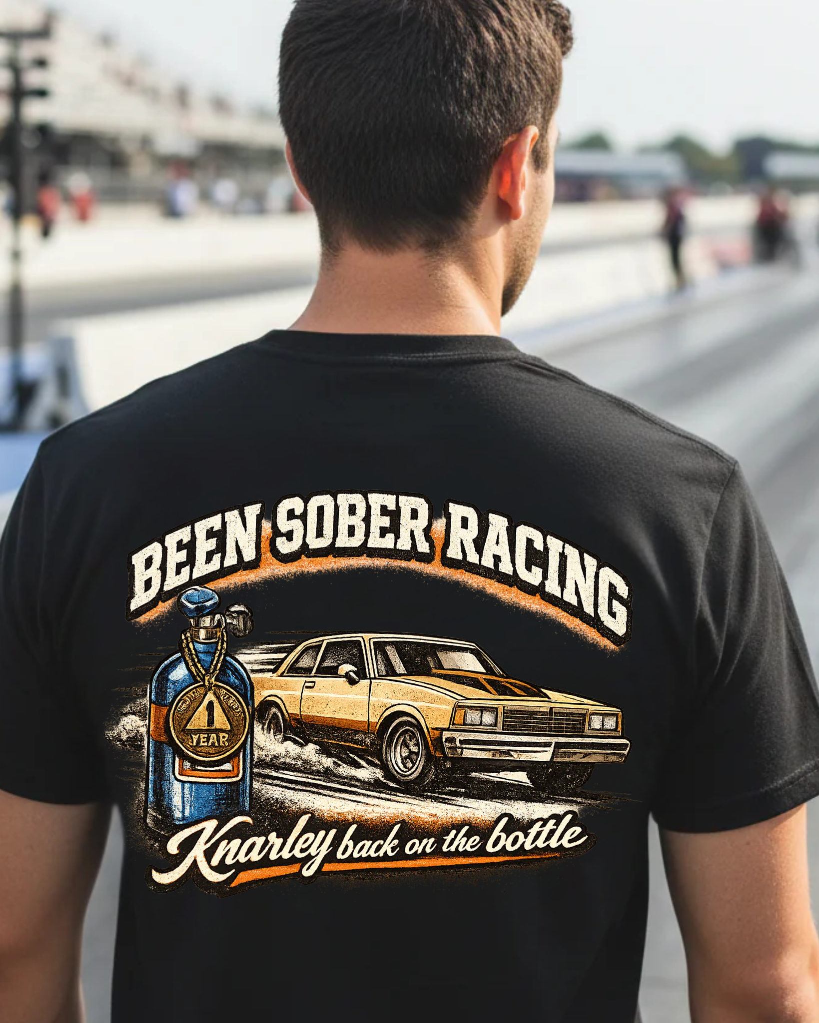 Person wearing a black t-shirt with 'Been Sober Racing' graphic at a race track.
