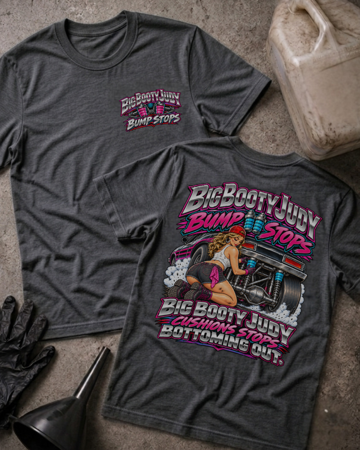Dark Grey Heather Big Booty Judy Bump Stops T-shirt, front and back views with a chest logo and pinup-style woman beside a drag car, plus “Big Booty Judy cushions stops bottoming out.”