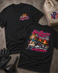 Two black graphic T-shirts displayed on a textured gray surface with racing-themed props, including a jerrycan, gloves, and funnel. The front shirt shows a small chest graphic, while the back shirt features a large colorful racing pin-up girl and race car graphic with the text 'Big Booty Judy Racing Club' and 'On A Pass Gapping Your Ass'.