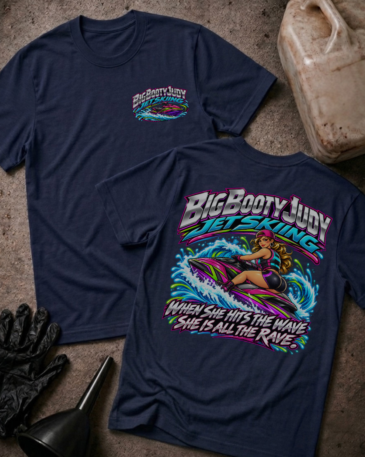 Navy Big Booty Judy Jet Skiing T-shirt, showing a small front chest logo and colorful back graphic of Judy riding a jet ski with “When she hits the wave she is all the rave.”