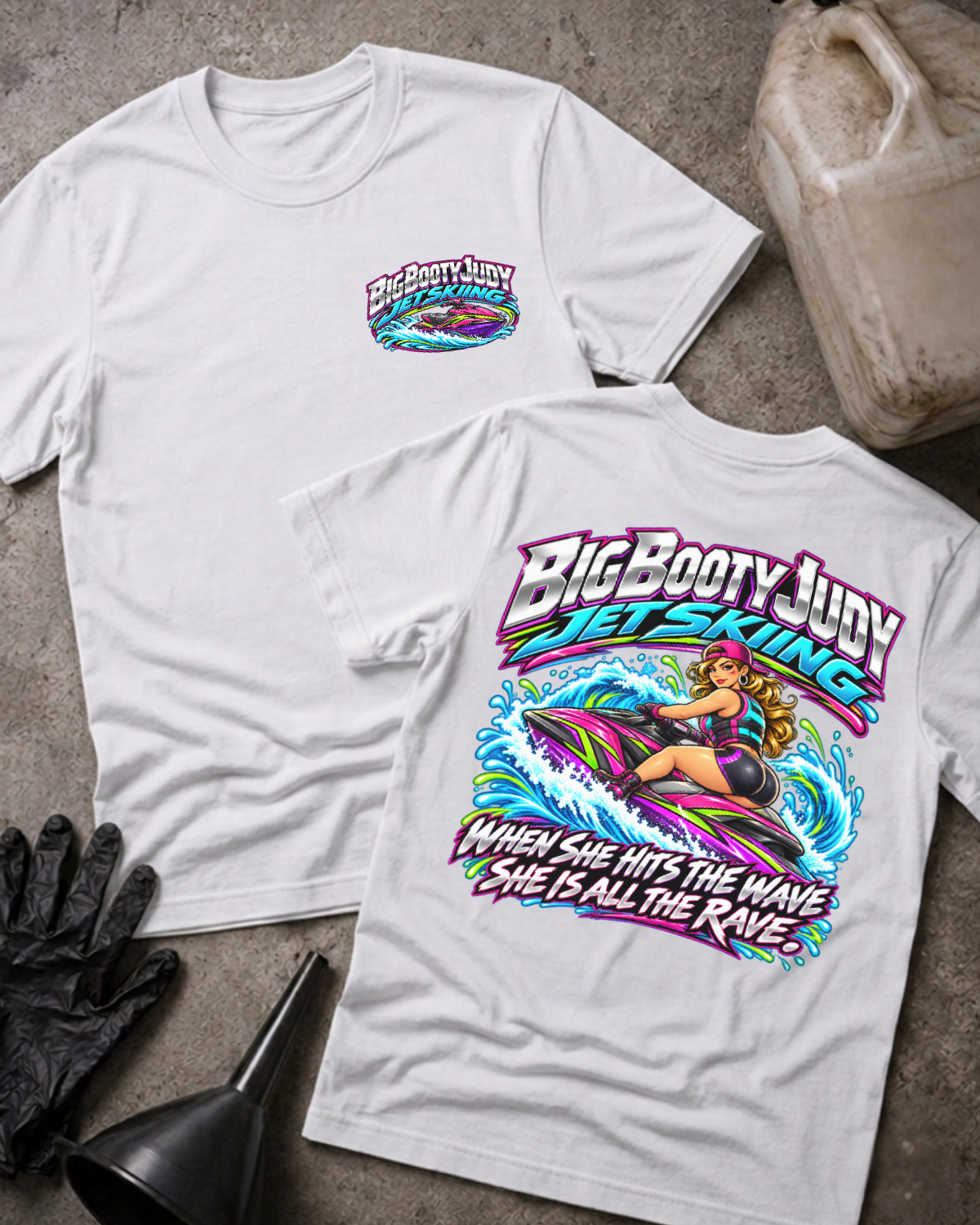 White Big Booty Judy Jet Skiing T-shirt, showing a small front chest logo and colorful back graphic of Judy riding a jet ski with “When she hits the wave she is all the rave.”