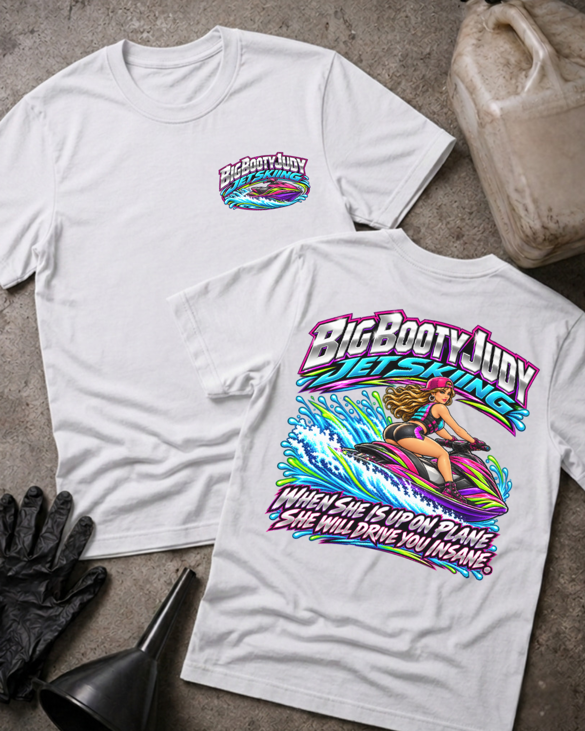 White Big Booty Judy Jet Skiing T-shirt showing a small chest logo and colorful back graphic of a woman riding a jet ski, with “When she is up on plane she will drive you insane.”