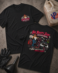Two black graphic T-shirts laid flat on a gray concrete surface, with a large illustrated race car and the text 'Big Booty Judy Race Seat Special' on the back and a smaller matching chest graphic on the front. A plastic jug labeled VP Racing, black gloves, and a funnel are placed around them as styling props.