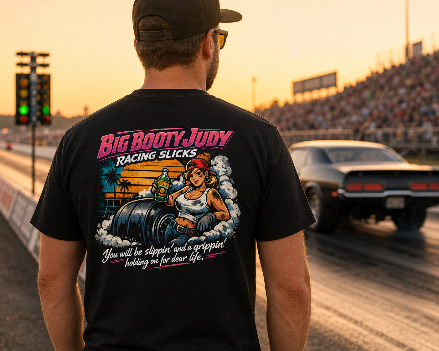 Person wearing a black t-shirt with a Big Booty Judy Racing Racing Slicks design at a race track.