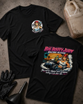 Two black graphic T-shirts laid flat on a textured gray surface, with racing-themed artwork and the text 'BIG BOOTY JUDY RACING SLICKS.' One shirt shows a small circular chest graphic, and the other shows a large back graphic with a pin-up style illustration and colorful text.