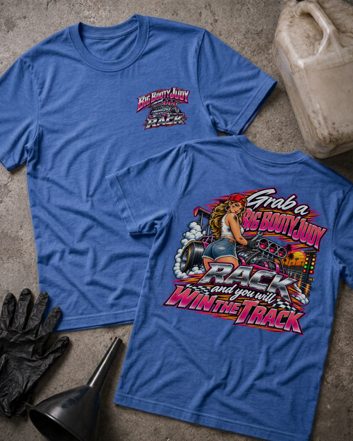 Big Booty Judy Rack To Win The Track T-shirt in heather true royal blue, flat lay showing the front chest logo and the back graphic reading Grab a Big Booty Judy Rack and You Will Win the Track, styled with work gloves, a funnel, and a fluid jug.