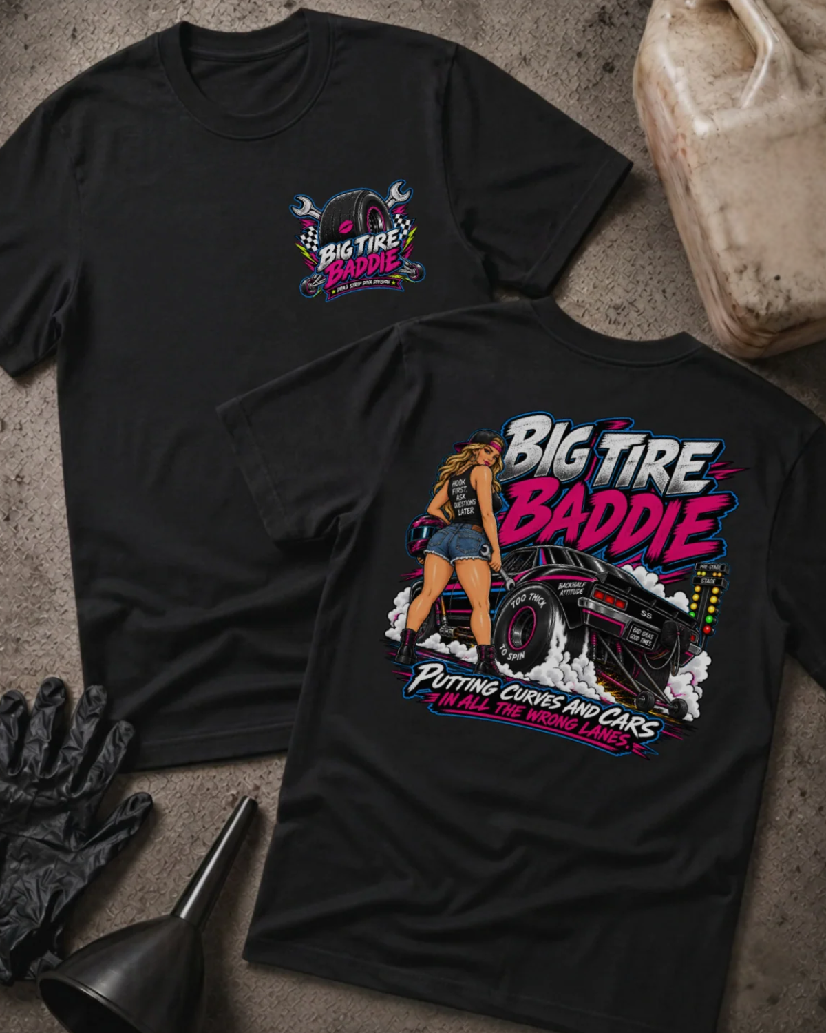 Front and back of Big Tire Baddie black T-shirt with chest logo, woman beside a drag car with wide rear tires, and “Putting curves and cars in all the wrong lanes” slogan.