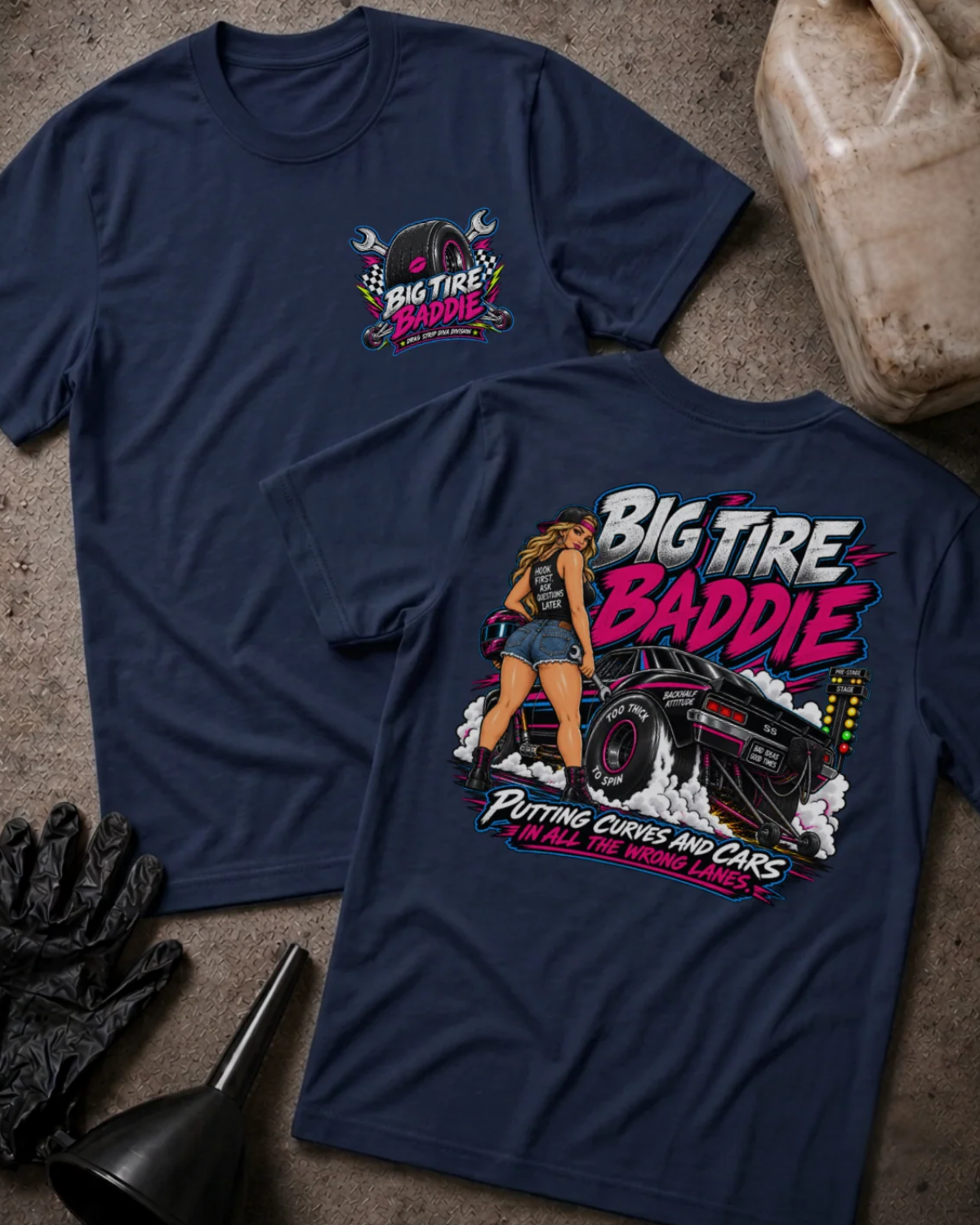 Front and back of Big Tire Baddie navy T-shirt with chest logo, woman beside a drag car with wide rear tires, and “Putting curves and cars in all the wrong lanes” slogan.