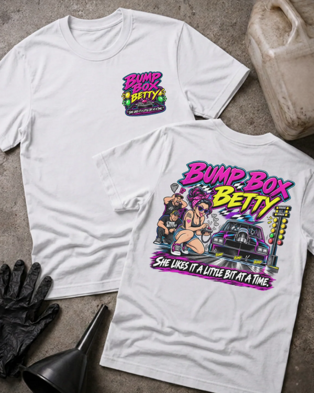 Front and back of Bump Box Betty white T-shirt with chest logo, woman using a handheld controller beside a drag car and staging lights, and “She likes it a little bit at a time” slogan.