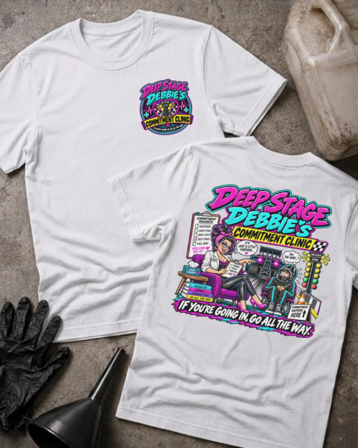 Front and back of Deep Stage Debbie’s Commitment Clinic white T-shirt with chest logo, woman counseling a helmeted racer beside staging lights, and “If you’re going in, go all the way” slogan.