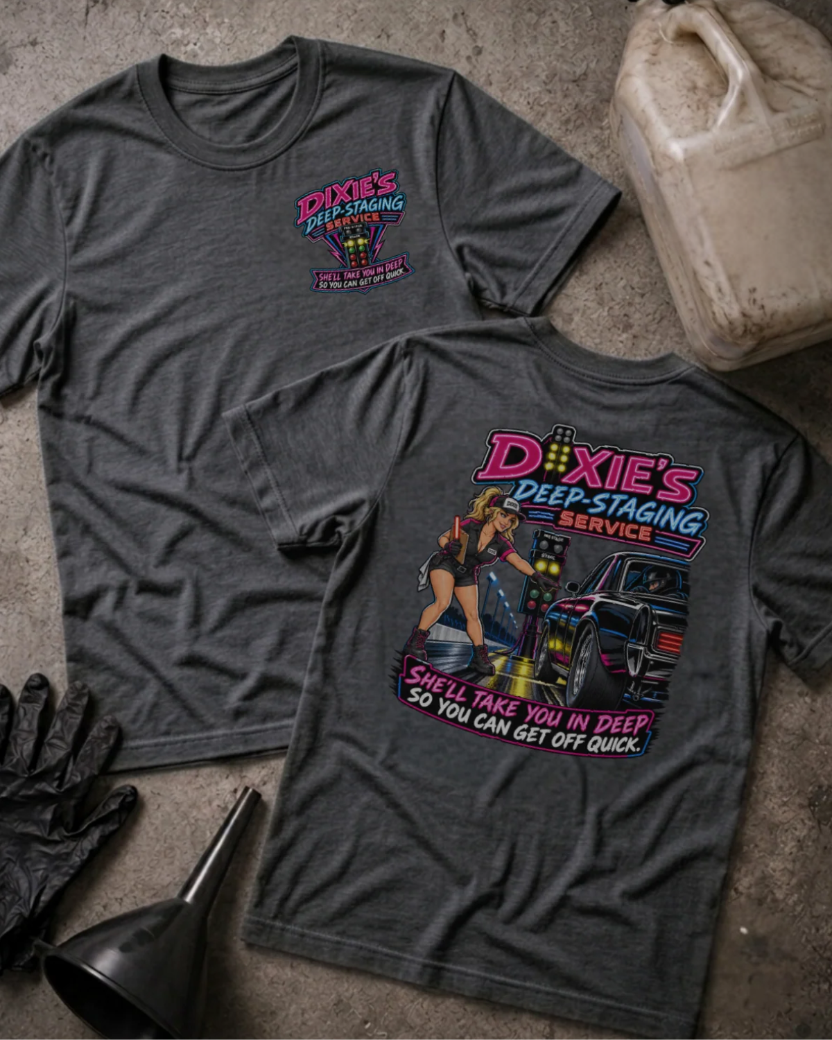 Front and back of Dixie’s Deep Staging Service dark grey heather T-shirt with chest logo, woman beside a drag car and staging lights, and “She’ll take you in deep so you can get off quick” slogan.