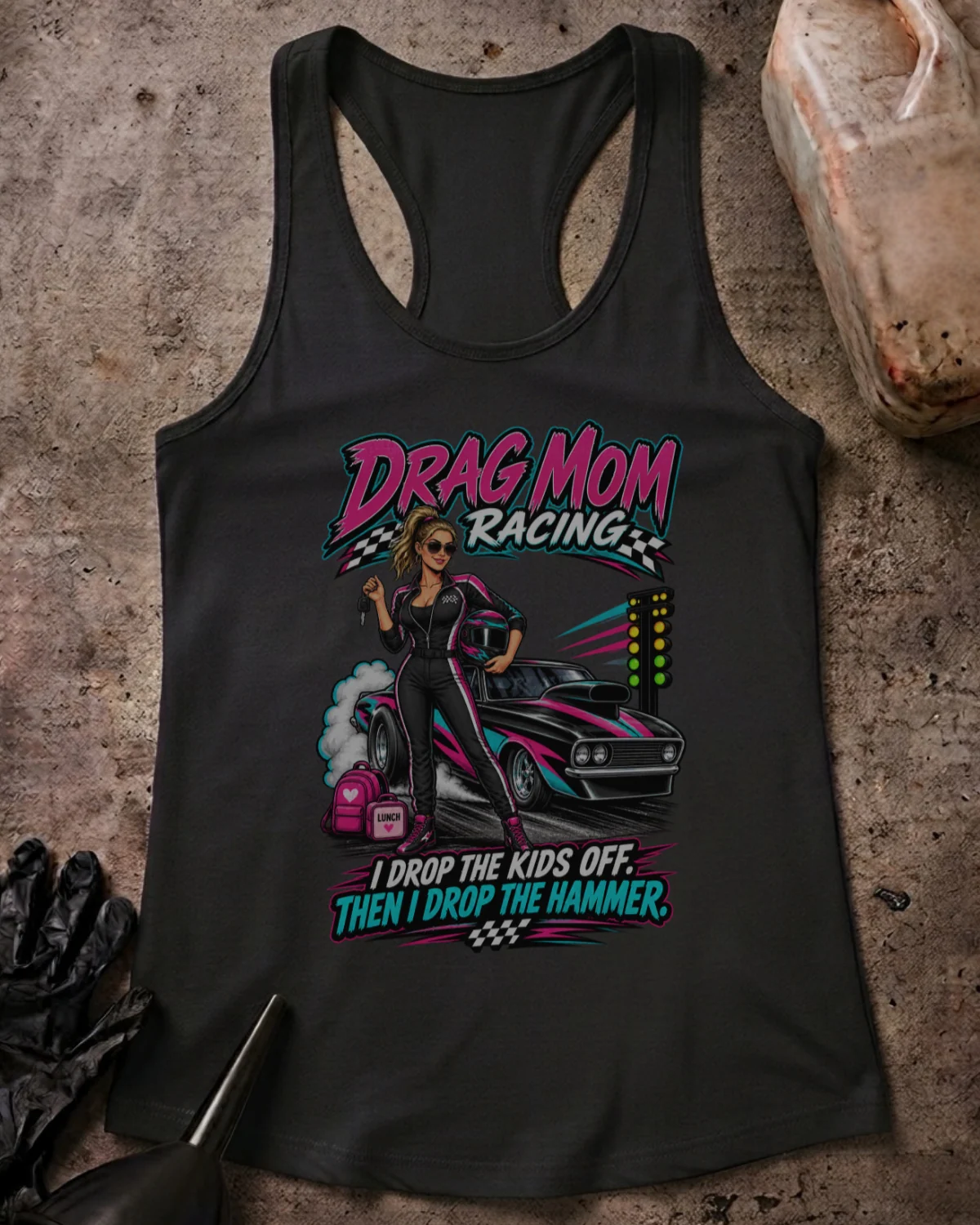 Front of Drag Mom Racing solid black racerback tank with woman in a racing suit beside a drag car and “I drop the kids off. Then I drop the hammer” slogan.