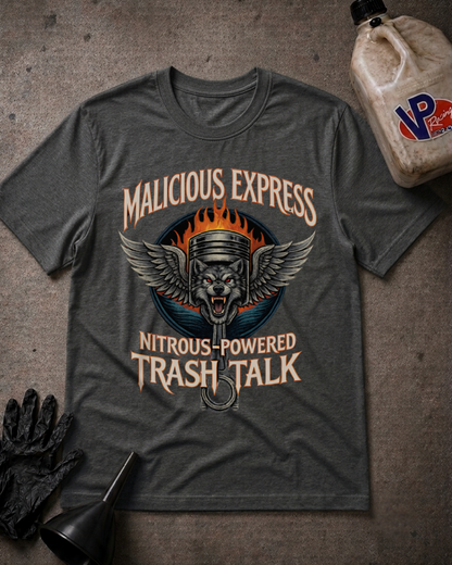 A dark heather gray graphic t-shirt laid flat on a textured gray surface, surrounded by racing-themed props including a black glove, a funnel, and a plastic jug of VP Performance fuel. The t-shirt features a graphic of a wolf piston with wings and flames, with the text 'MALICIOUS EXPRESS' and 'NITROUS-POWERED TRASH TALK'.
