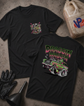 Two black 'DRAGGIN WAGGIN' graphic T-shirts laid flat on a textured gray surface, with racing-themed printed artwork and text. A black glove, funnel, and a plastic fuel can are placed around them as styled props.