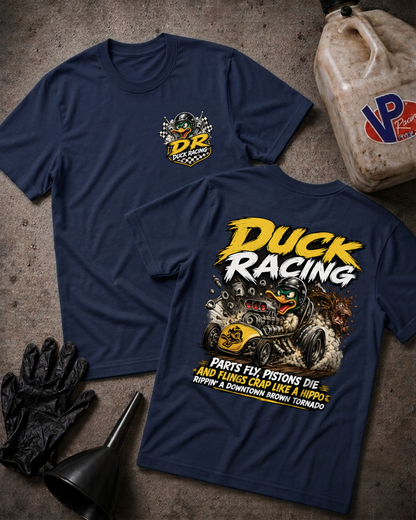 Two navy blue t-shirts shown flat on a textured gray surface, displaying the front and back of a 'Duck Racing' graphic design. The shirt features a yellow and white chest logo on the front, and a large yellow and white 'Duck Racing' graphic with a cartoon duck and car on the back.