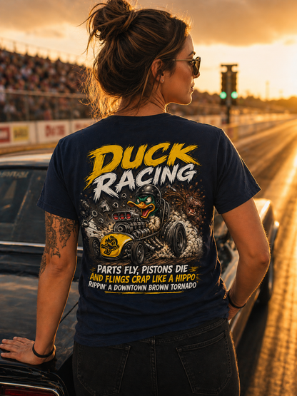 Woman wearing a 'Duck Racing' t-shirt on a race track at sunset.