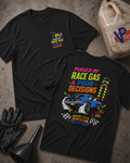 Two black graphic T-shirts laid flat on a textured gray surface, with racing-themed printed artwork and 'FUELED BY RACE GAS AND POOR DECISIONS'  text. One shirt shows a small multicolor chest graphic, and the other shows a larger back print featuring a blue race car, neon-style text, and checkered details.
