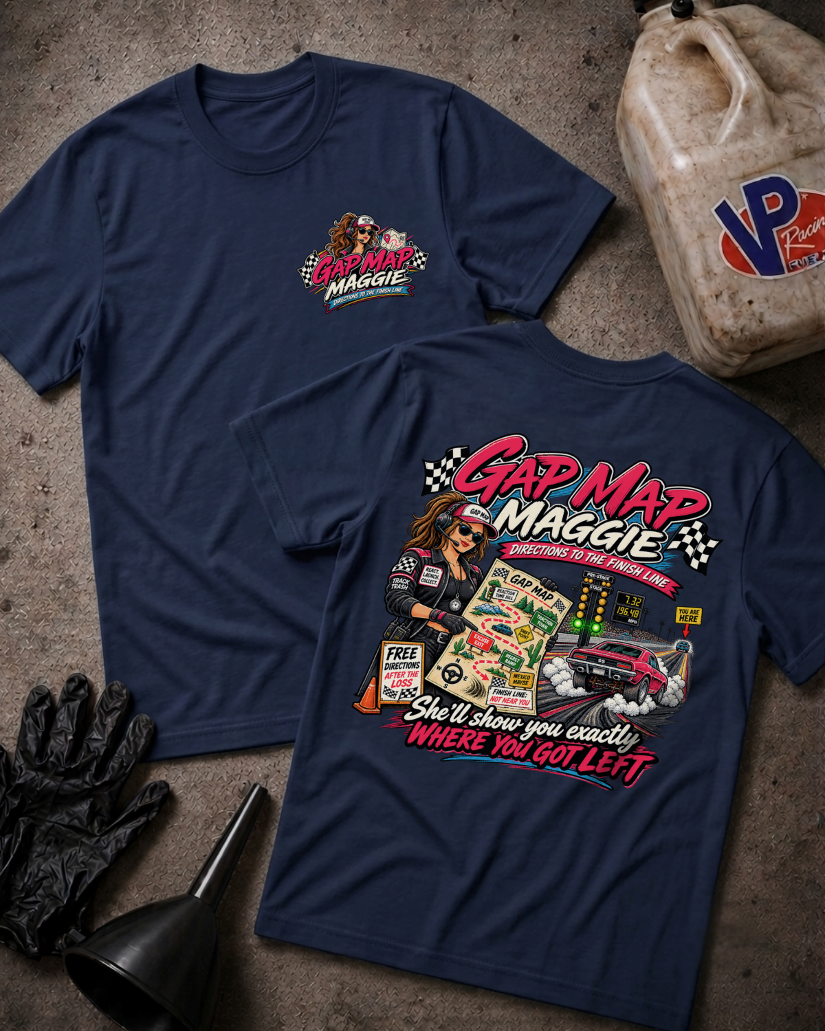 Two navy blue graphic T-shirts laid flat on a textured gray surface, with automotive-themed printed artwork on the chest and back. A plastic jug, black gloves, and a funnel are placed around them as styled props.