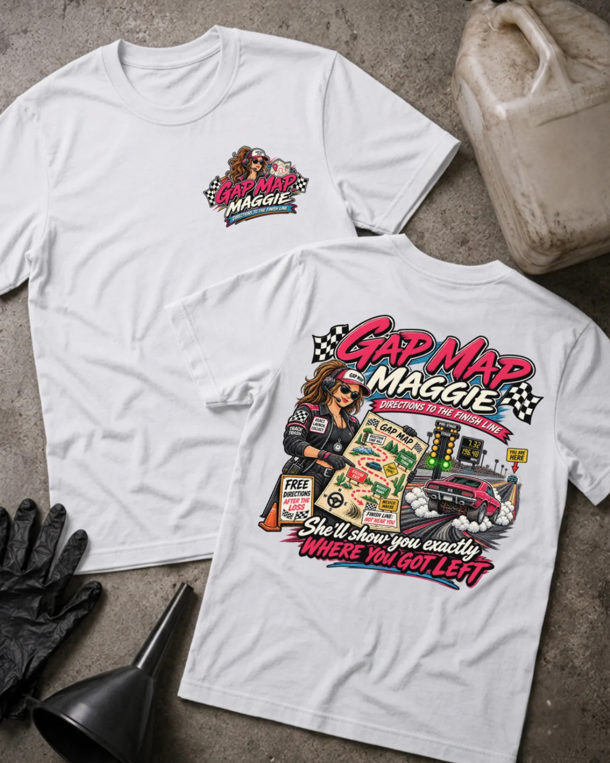 Two white graphic T-shirts laid flat on a concrete surface, showing the front and back designs. The shirts feature a colorful 'Gap Map Maggie' racing graphic with a cartoon woman in a racing suit, checkered flags, a race car, and the phrase 'She'll show you exactly WHERE YOU GOT LEFT'.