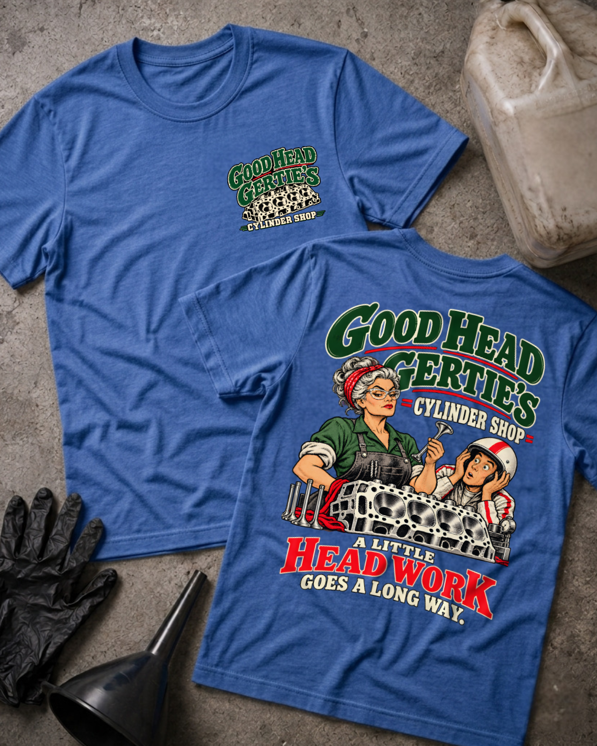 Heather royal blue Good Head Gertie’s Cylinder Shop T-shirt showing the front chest logo and back cartoon of a woman machinist machining a cylinder head beside a racer in a helmet, “A Little Head Work Goes a Long Way,” with gloves, funnel, and oil jug.