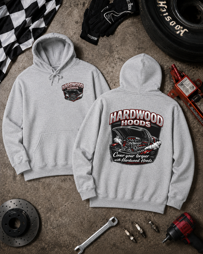 Gray hoodie with 'Hardwood Hoods' branding on a textured surface with automotive tools and parts.