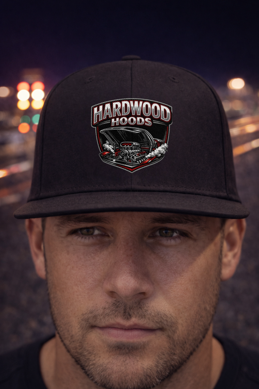 Man wearing a black cap with 'Hardwood Hoods' logo against a blurred drag strip background