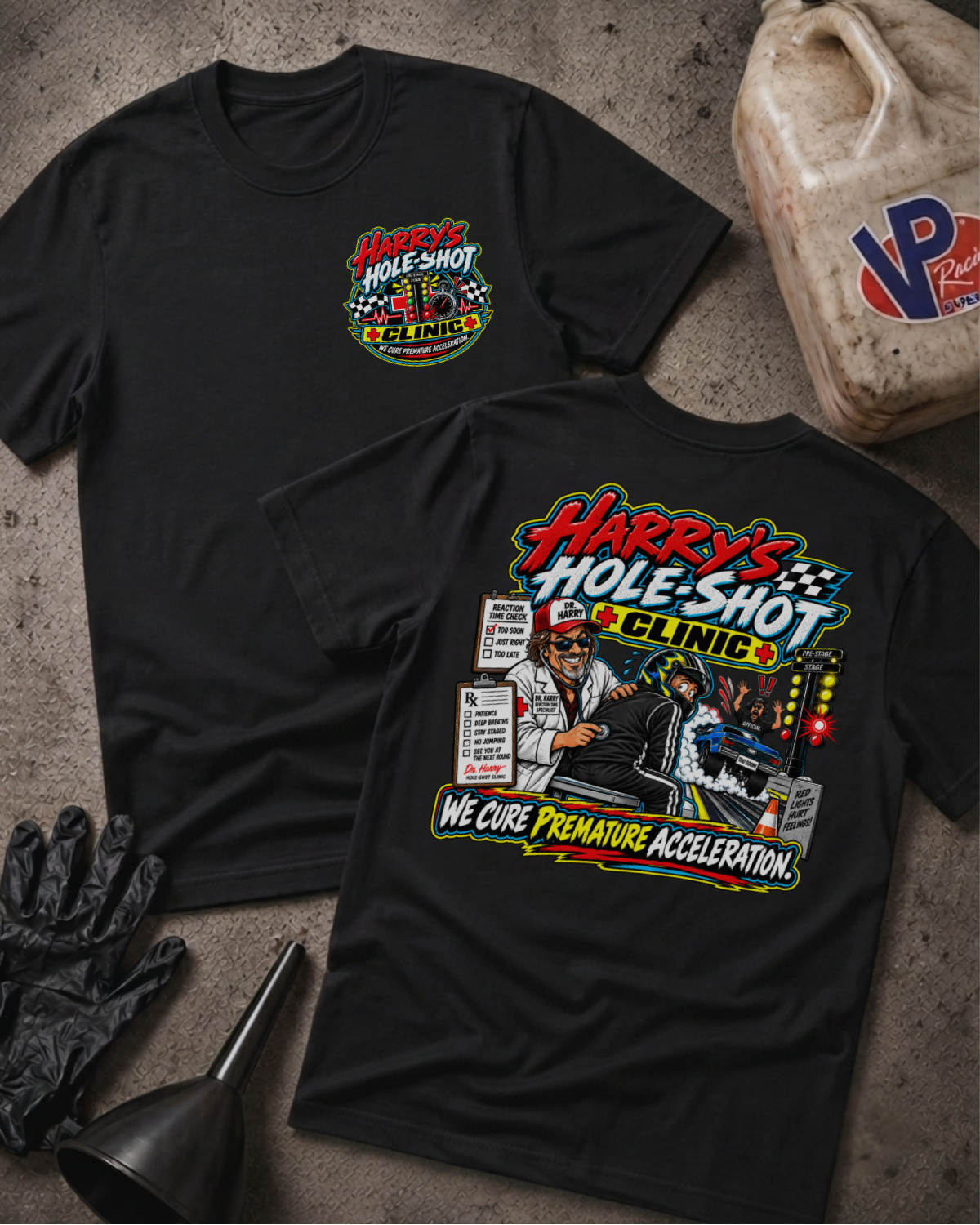 Two black graphic T-shirts laid flat on a textured gray surface, showing front and back designs for 'Harry's Hole-Shot Clinic'. A plastic jug, black gloves, and funnel are styled around the shirts.