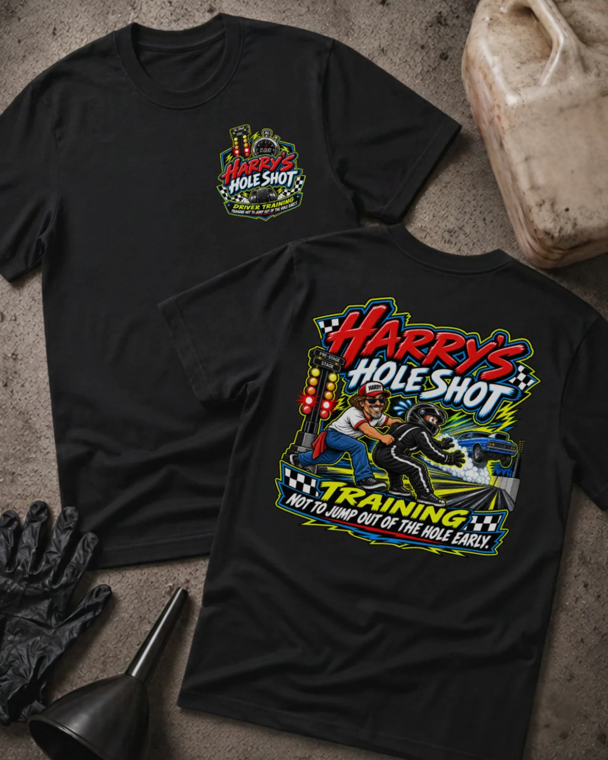 Front and back of Harry’s Hole Shot Training black T-shirt with chest logo, instructor holding back a helmeted racer beside staging lights, and “Not to jump out of the hole early” slogan.