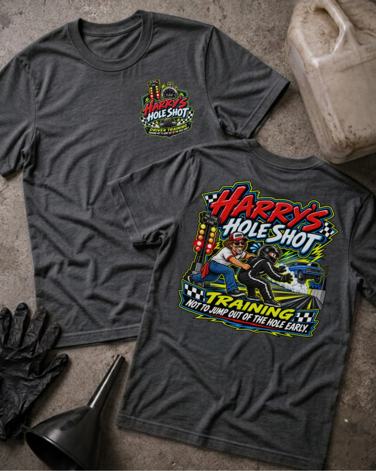 Front and back of Harry’s Hole Shot Training dark grey heather T-shirt with chest logo, instructor holding back a helmeted racer beside staging lights, and “Not to jump out of the hole early” slogan.