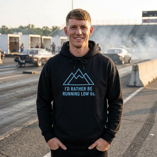 Man wearing a black hoodie with a humorous graphic and 'I'd Rather Be Running Low 6s' text on a race track.