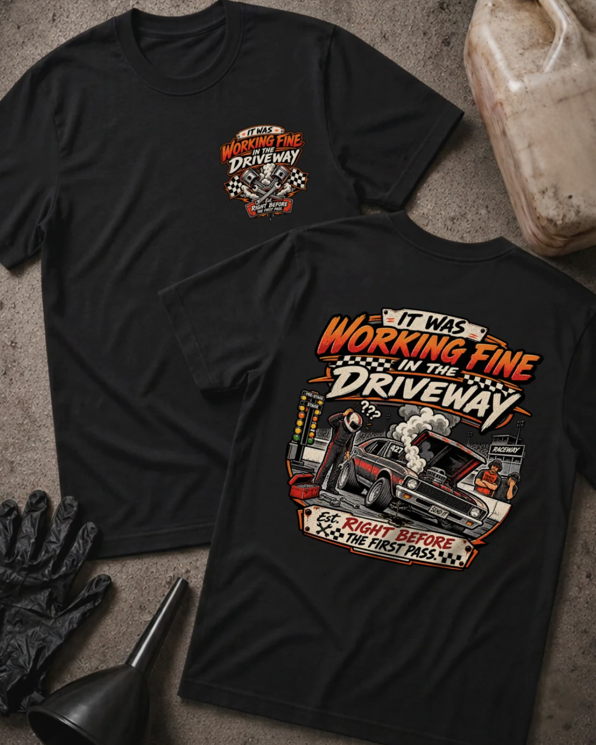 Front and back of It Was Working Fine in the Driveway black T-shirt with chest logo, smoking muscle car with open hood at a drag strip, and “Right before the first pass” text.