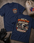Two navy graphic T-shirts displayed on a concrete floor, with a vintage car, funnel, gloves, and a VP Racing fuel canister nearby. The front shirt shows a small chest graphic, and the back shirt shows a large graphic reading 'It Was Working Fine in the Driveway' with a car and race-themed illustration.