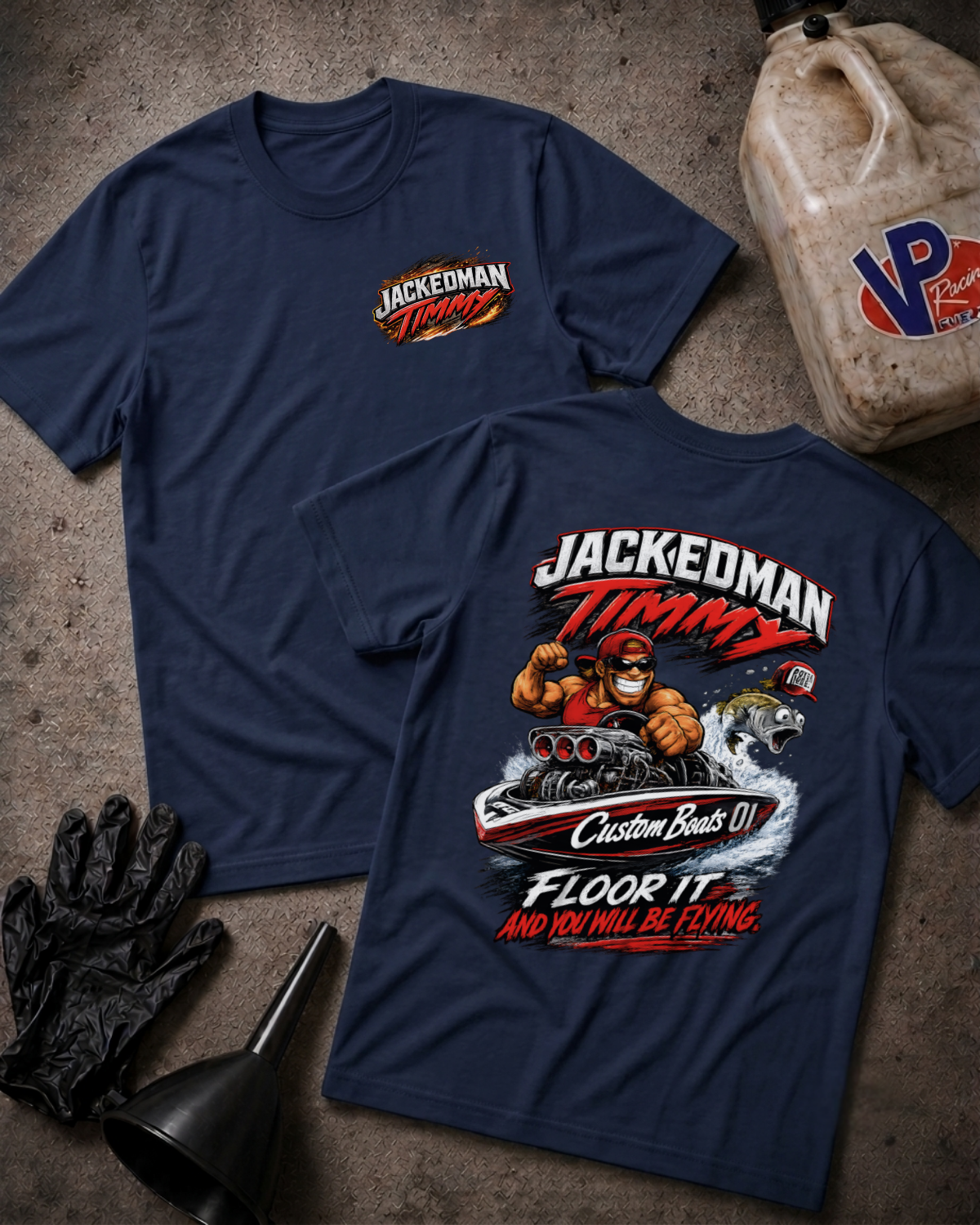 Two navy blue t-shirts displayed flat on a textured gray surface, showing the front and back graphics. The front features a small 'Jackedoman Timmy' logo on the left chest, while the back displays a large graphic of a man driving a boat with the text 'JACKEDOMAN TIMMY Custom Boats 01 FLOOR IT AND YOU WILL BE FLYING.