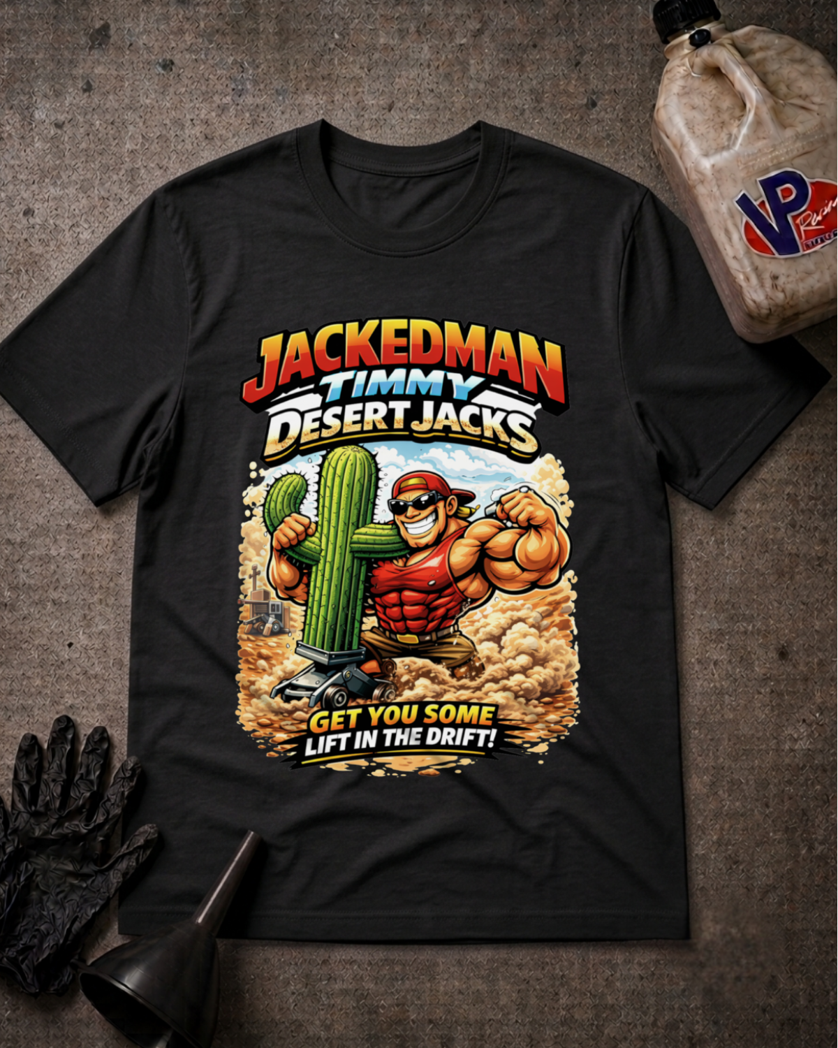 A black graphic t-shirt laid flat on a textured gray surface, featuring a 'JACKEDMAN TIMMY DESERT JACKS' design. The shirt is styled with a black oil bottle, a black glove, and a funnel.