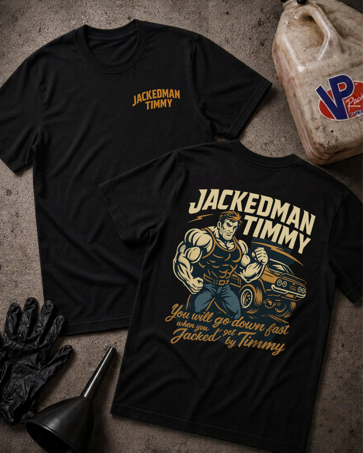 Two black graphic T-shirts laid flat on a textured concrete-like surface, with  gloves, funnel, and oil container as props. The front shirt shows a small gold 'JACKEDMAN TIMMY' logo on the left chest, and the back shirt shows a large vintage-style muscular driver illustration with the text 'JACKEDMAN TIMMY' and 'You will go down fast when you get Jacked by Timmy.