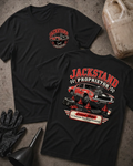 Front and back of Jackstand Proprietor black T-shirt with chest logo, weathered red muscle car on jack stands, and “Current status: 3–5 business days from a breakdown” slogan.