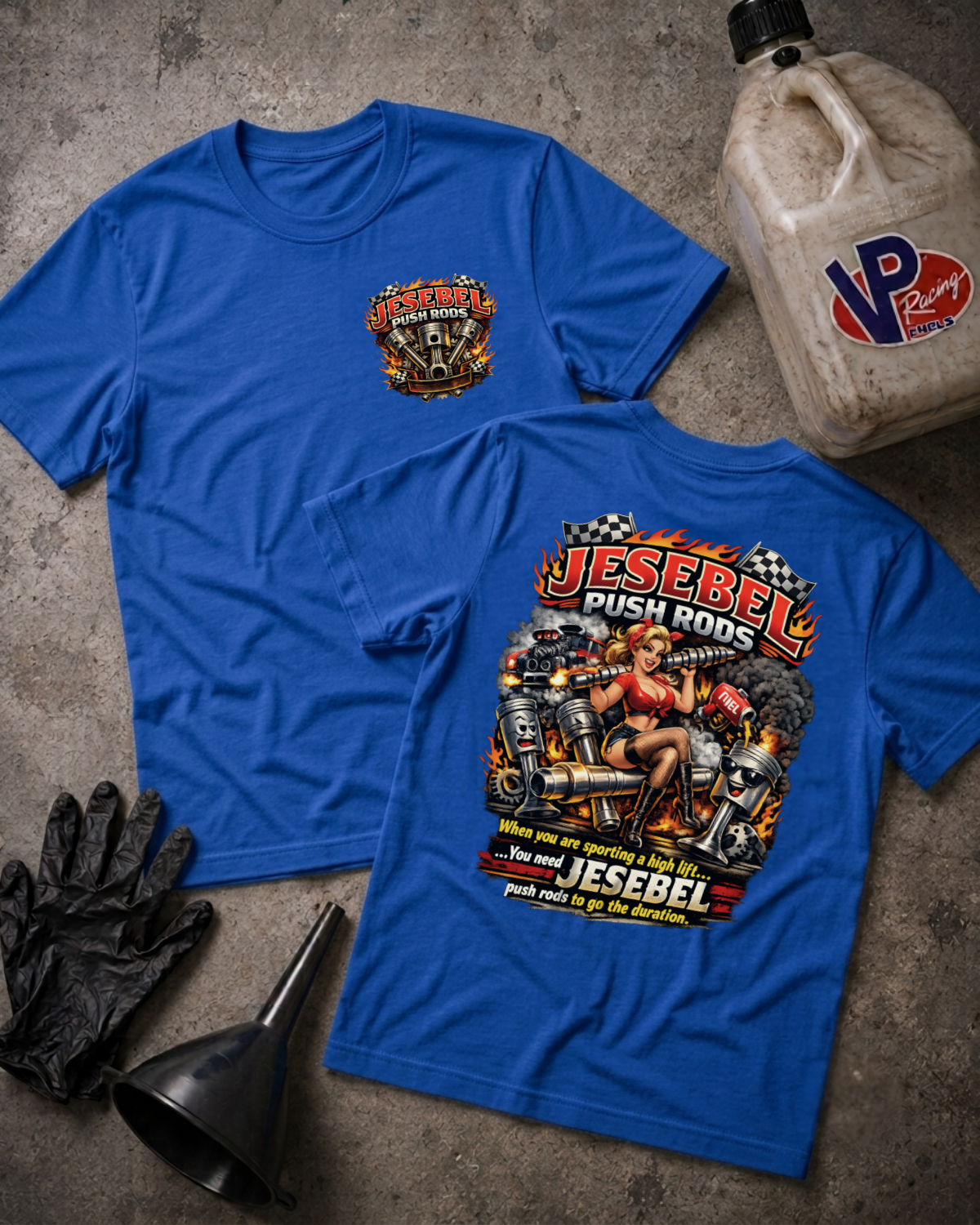Two blue graphic T-shirts laid flat on a gray concrete surface, with a large front chest print and a larger back graphic featuring a woman on a push rod and the words 'Jesebel Push Rods.' A beige VP Racing fuel jug, black gloves, and a black funnel are placed around them as props.