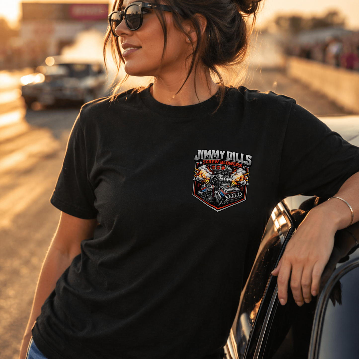 Woman wearing black car guy t-shirt with small Jimmy Dills Screw Blowers logo at drag strip