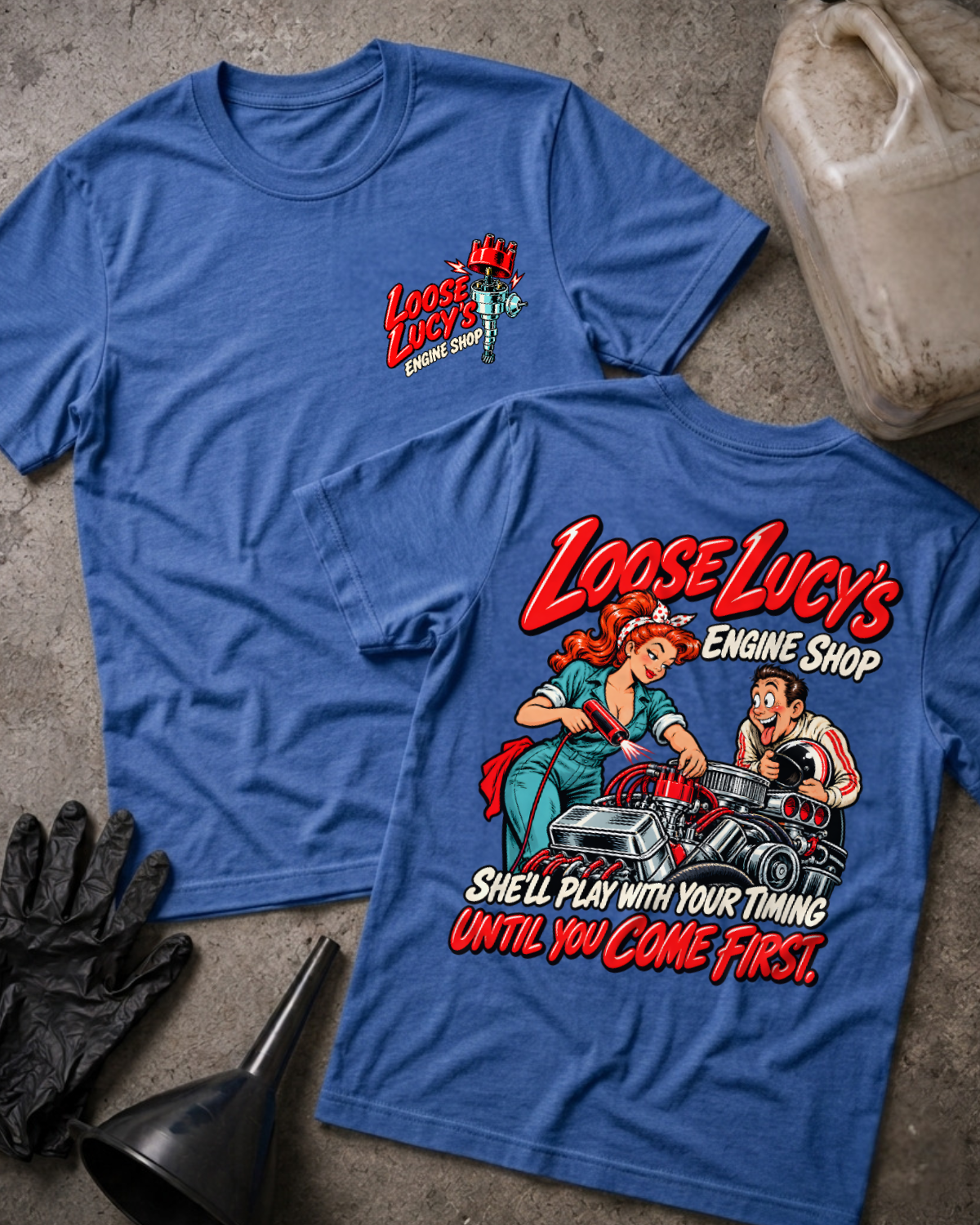 Heather royal blue Loose Lucy’s Engine Shop T-shirt showing the front chest logo and back cartoon of a woman mechanic timing a hot rod engine with a timing light, “She’ll Play With Your Timing Until You Come First,” with gloves, funnel, and oil jug props.