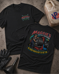 Two black short-sleeve T-shirts shown on a textured concrete-style surface, with the front and back views overlapping. The front has a small colorful 'Maggie's Mounting & Balancing' logo on the left chest.
