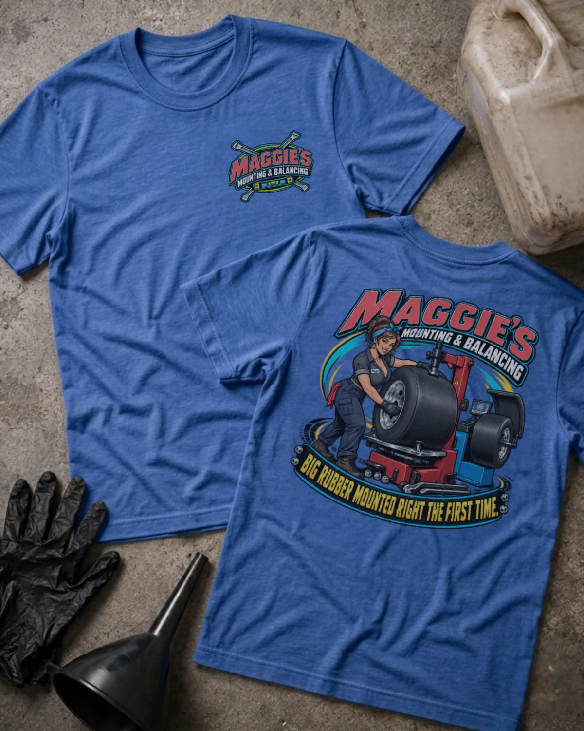 Front and back of Maggie’s Mounting & Balancing heather true royal T-shirt with chest logo, woman working with tire equipment, and “Big rubber mounted right the first time” slogan.