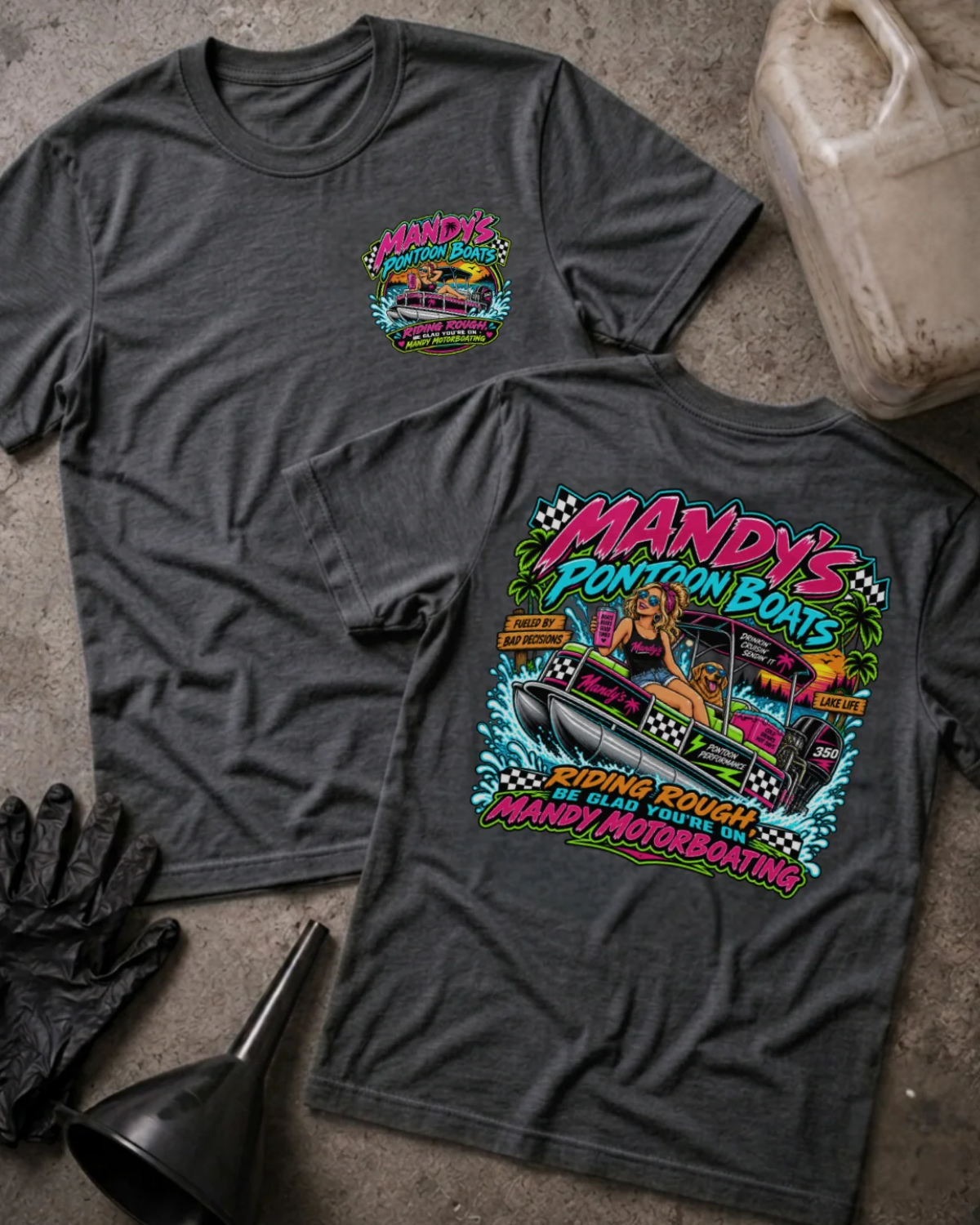 Front and back of Mandy’s Pontoon Boats dark grey heather T-shirt with chest logo, woman and dog aboard a pontoon boat, and “Riding rough? Be glad you’re on Mandy Motorboating” slogan.