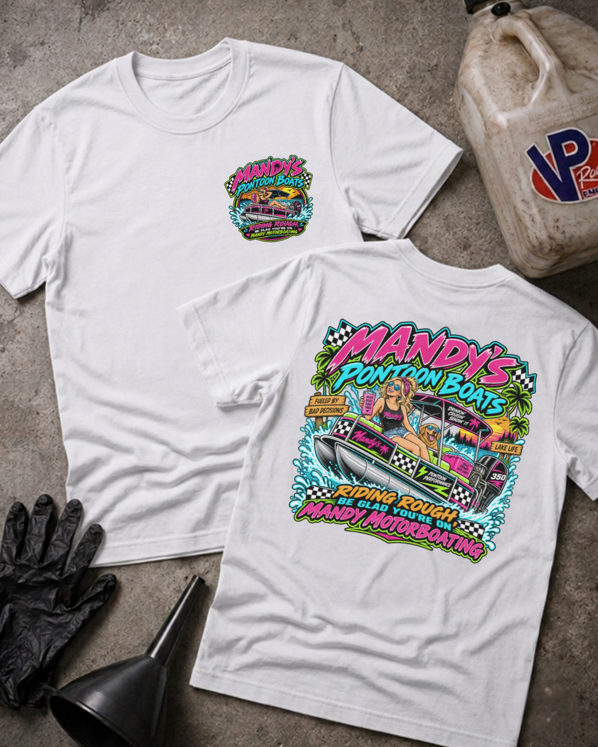 Two white graphic T-shirts laid flat on a concrete surface, showing the front and back designs. The shirts feature colorful graphics for 'Mandy's Pontoon Boats' with a boat illustration and bold text.
