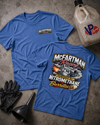 Two blue short-sleeve t-shirts laid flat on a gray concrete surface, with a black funnel, black gloves, and a plastic jug. The front shirt has a small McFartman Racing logo on the left chest, and the back shirt has a large graphic with a turbo engine, flames, and the text 'McFartman Racing' and 'Nitromethane Burritos'.