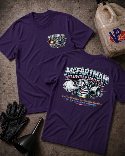 Two purple short-sleeve graphic T-shirts laid flat on a textured gray surface, with a black funnel, black gloves, and a beige plastic jug used as styling props. The front shirt shows a small chest graphic reading McFartman, and the back shirt shows a large graphic with the same brand name, a cartoon blower valve character, and smaller text.